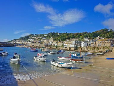 A coastal village with boats anchored in the water and houses on a hillside at Mermaid Cottage in Mousehole