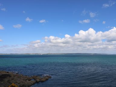 A coastal view with rocky shoreline and sea under a partly cloudy sky at Mermaid Cottage in Mousehole