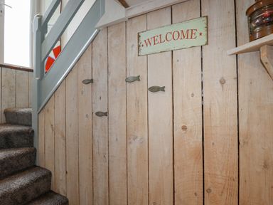 A wooden staircase with carpeted steps and a welcome sign on the wall at Sailor's Rest in Newquay