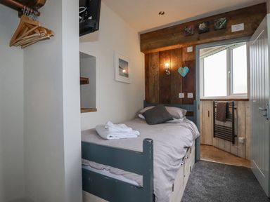 A small bedroom with a single bed and wooden hangers on a rail at Sailor's Rest in Newquay