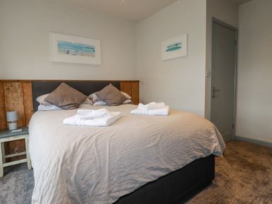 A bedroom with a bed folded towels on the bed and framed pictures on the walls at Sailor's Rest in Newquay