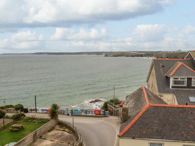 A coastal view with a road along the shore and houses with tiled roofs at Sailor's Rest in Newquay