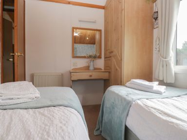 A bedroom with two beds and a mirror at The Cedars South Lakeland Leisure Village