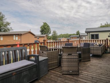 A deck with outdoor chairs and table at The Cedars in South Lakeland Leisure Village