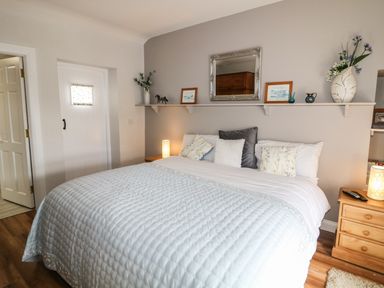 A bedroom with a bed pillows bedside tables lamps and decorative items on a shelf above the bed at Mary Larkins Cottage Rostrevor near Newry