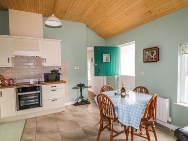A kitchen with a stove, microwave, dining table with four chairs, and a green half door at Pat White's Cottage in Rostrevor
