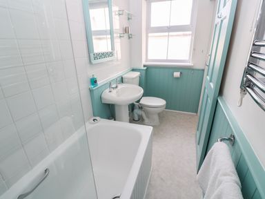 A bathroom with a bathtub a sink a toilet a mirror and a window at Beachcomber in Marazion