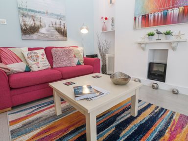 A living room with a pink sofa and coffee table at Beachcomber in Marazion