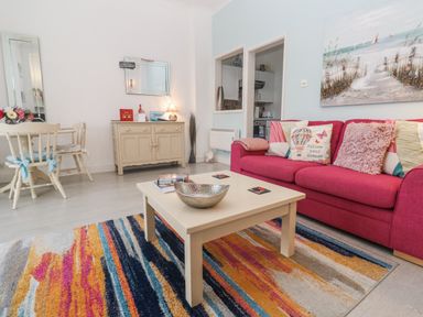 A living room with a sofa, coffee table, and dining table at Beachcomber in Marazion