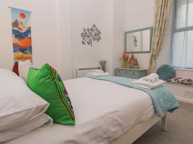 A bedroom with a bed, mirror, and decorative items at Beachcomber in Marazion