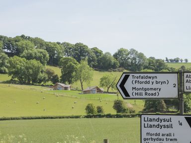 A countryside scene with road signs and houses in a field at Shepherd's Rest in Montgomery