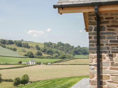 A stone house wall with pipe overlooking green fields and hills at Shepherds Rest in Montgomery