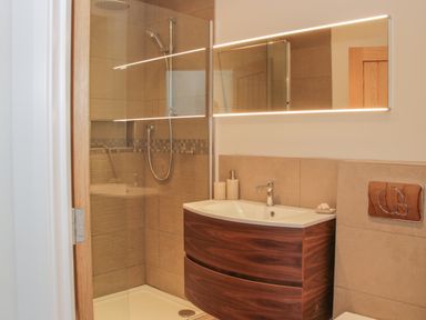 A bathroom with a shower enclosure wooden sink cabinet and illuminated mirror at Shepherd's Rest in Montgomery