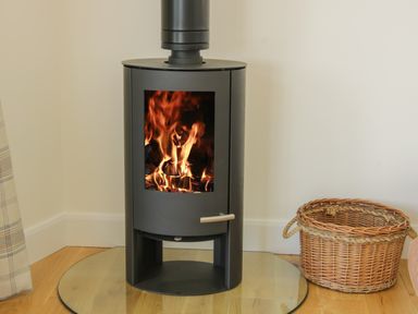 A wood burning stove with fire inside next to a wicker basket at Shepherd's Rest in Montgomery