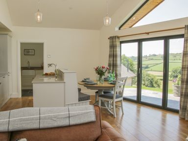 A dining area with a round table and chairs near large sliding glass doors showing a countryside view at Shepherd's Rest in Montgomery