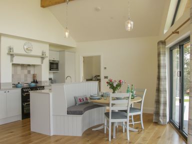 A kitchen and dining area with a round table set with dishes and a bench seat next to sliding glass doors at Shepherds Rest in Montgomery