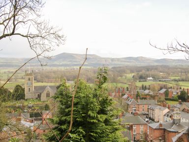A village with a church tower surrounded by trees and houses with hills in the background at Shepherd's Rest in Montgomery