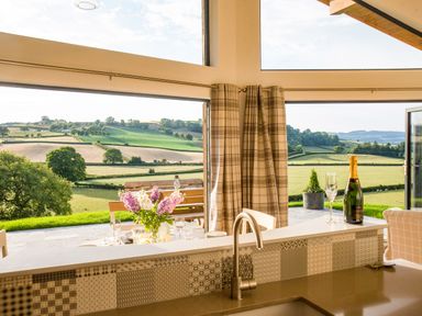 Kitchen interior with a sink and counter facing open doors to a patio with table flowers and countryside view at Shepherd's Rest in Montgomery