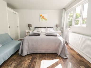 A bedroom with a double bed covered with a gray quilt and two folded towels on it at Emblestones in Embleton