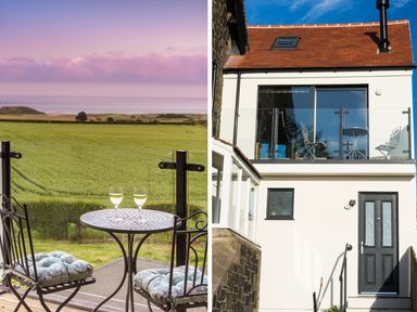 A balcony with a small round table and two chairs overlooking a green field and the sea at Emblestones in Embleton