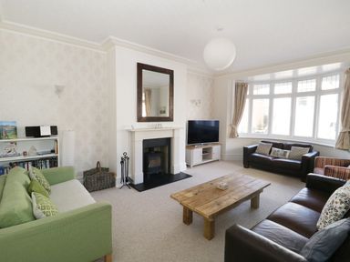 A living room with sofas a wooden coffee table a fireplace and a television at 20 Ulwell Road Swanage
