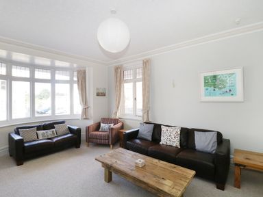 A living room with two leather sofas a striped armchair a wooden coffee table and framed artwork at 20 Ulwell Road in Swanage