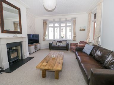 A living room with two leather sofas an armchair a wooden coffee table a fireplace and a television at 20 Ulwell Road in Swanage