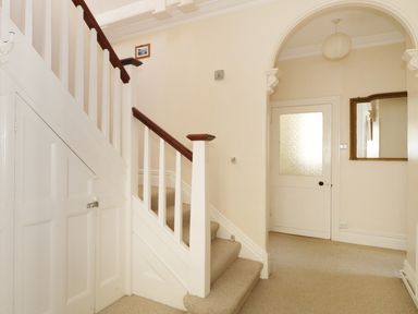 A hallway with carpeted stairs and a door with frosted glass at 20 Ulwell Road in Swanage