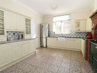 A kitchen with cream cabinets a stainless steel refrigerator a window above a sink and tiled floor at 20 Ulwell Road in Swanage