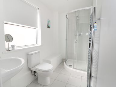 A bathroom with a shower enclosure toilet sink and a window at 20 Ulwell Road in Swanage