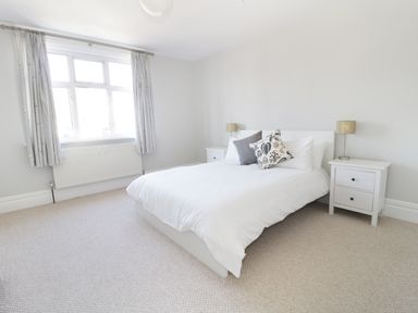 A bedroom with a double bed bedside tables and lamps by a window at 20 Ulwell Road Swanage