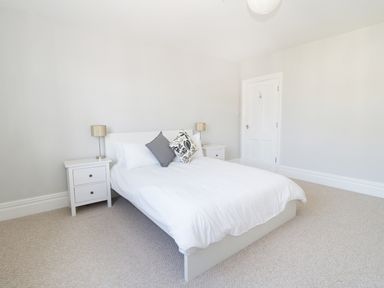 A bedroom with a double bed between two bedside tables each with a lamp at 20 Ulwell Road in Swanage