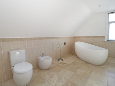 A bathroom with a toilet bidet standalone bathtub and a window at 20 Ulwell Road in Swanage