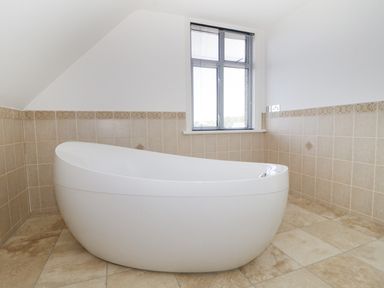 A bathroom with a freestanding bathtub and tiled walls and floor at 20 Ulwell Road in Swanage