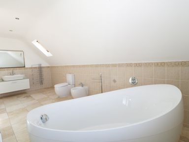A bathroom with a bathtub toilet bidet sink mirror and towel racks at 20 Ulwell Road Swanage