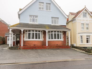 A detached house with a blue upper floor and brick lower floor featuring bay windows and a driveway at 20 Ulwell Road in Swanage