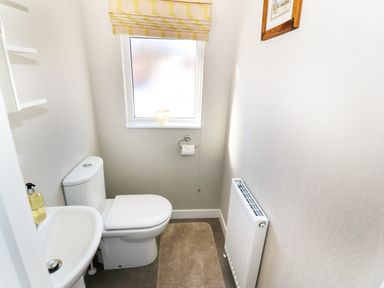 A small bathroom with a toilet sink window and radiator at 32 Cruachan Lodge in Auchterarder