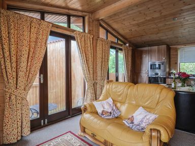 A living room with a yellow sofa and dining area at The Cabin at East Hill Pride Four Elms Hill Nr. Sidmouth