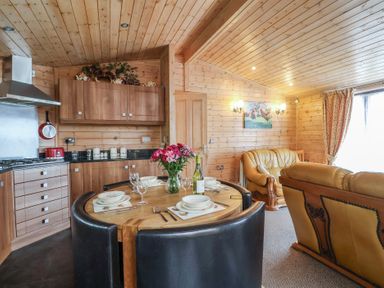 A dining area with a round table and brown leather sofa at The Cabin at East Hill Pride, Four Elms Hill Nr. Sidmouth