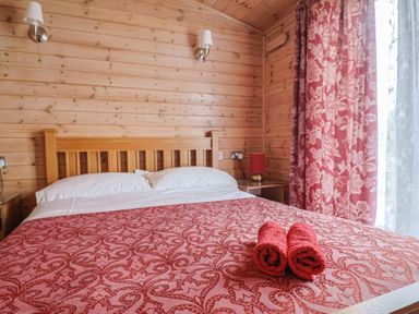 A bedroom with a bed and towels in a wooden cabin at The Cabin at East Hill Pride Four Elms Hill Nr. Sidmouth