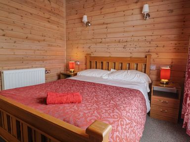 A bedroom with a wooden bed and bedside tables at The Cabin at East Hill Pride Four Elms Hill Nr. Sidmouth