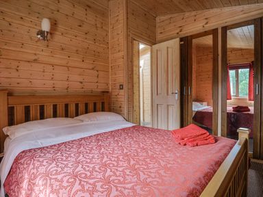 A bedroom with a double bed and wooden furniture at The Cabin at East Hill Pride Four Elms Hill Nr. Sidmouth