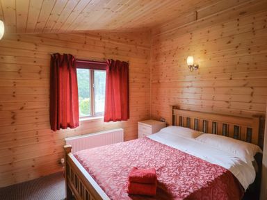 A bedroom with a bed and bedside table at The Cabin at East Hill Pride Four Elms Hill Nr. Sidmouth