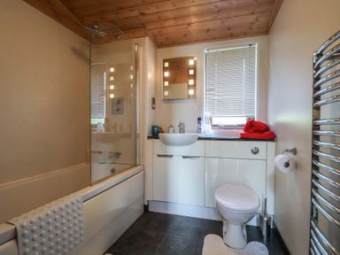 A bathroom with a shower over bathtub and sink at The Cabin at East Hill Pride Four Elms Hill Nr. Sidmouth