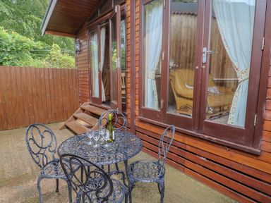 A table and chairs with a wine bottle and glasses at The Cabin at East Hill Pride Four Elms Hill Nr. Sidmouth