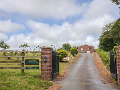 A gate and driveway leading to a building at The Cabin at East Hill Pride Four Elms Hill Nr. Sidmouth