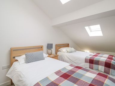 A bedroom with two single beds side by side with wooden headboards and a bedside table with a lamp at Coney Garth Barn in Beckermet