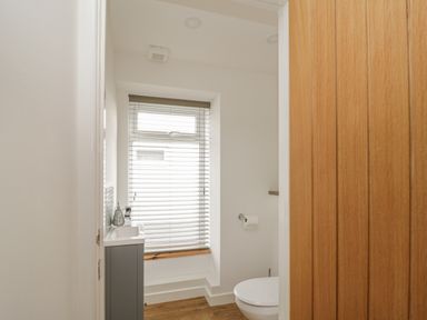 A small bathroom with a toilet sink and window blinds at Coney Garth Barn in Beckermet