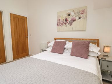 A bedroom with a bed and a painting at Coney Garth Barn in Beckermet