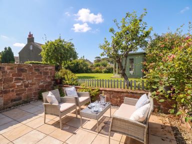 A garden with a patio seating area at Coney Garth Barn in Beckermet